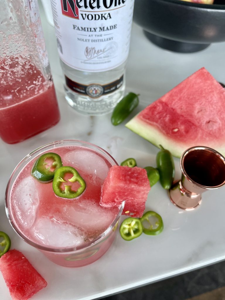 A sparkling watermelon vodka cocktail is in a chilled glass on a counter with Ketel One Vodka, watermelon juice and watermelon