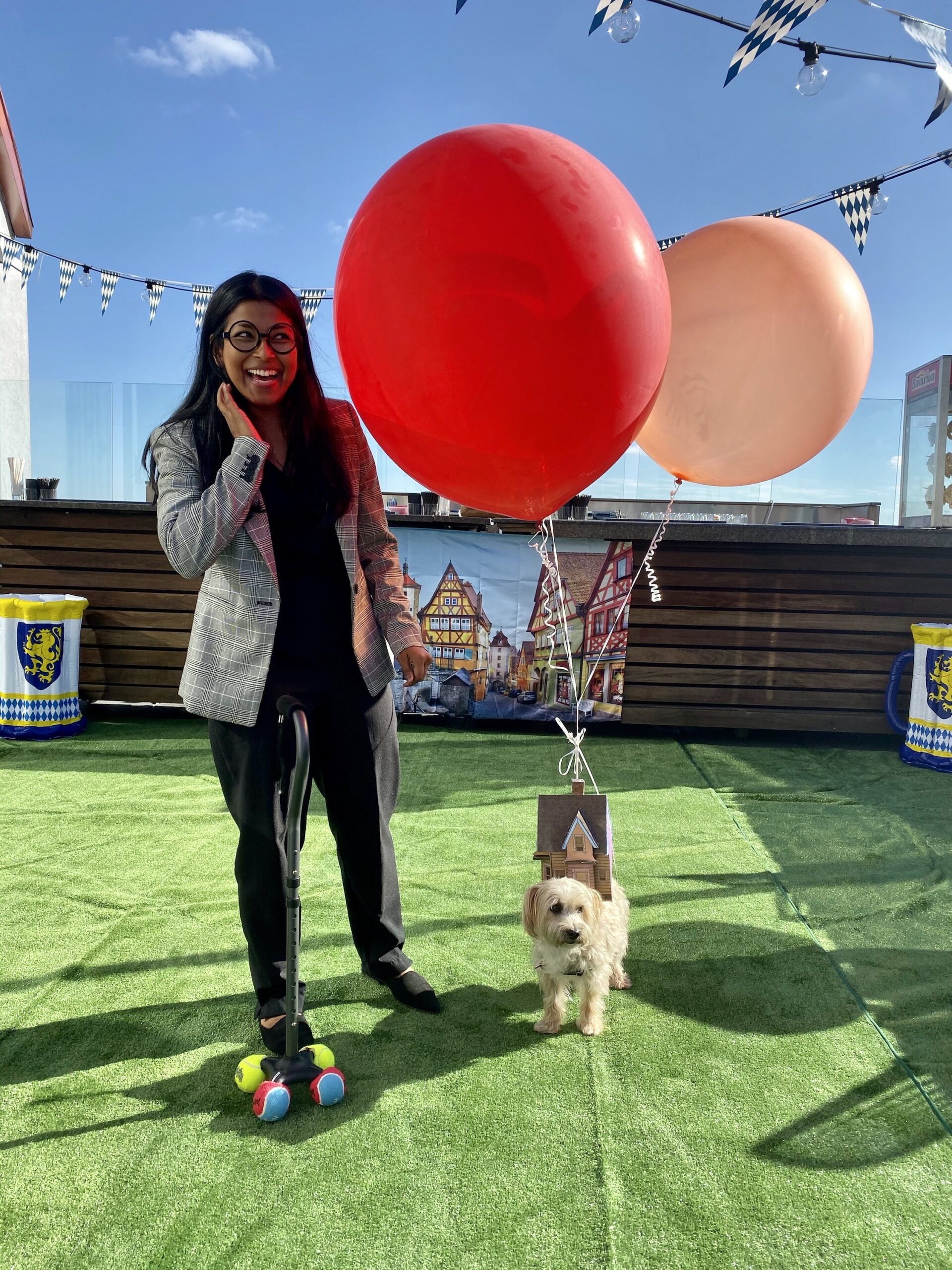 a women dressed as the old man from Up is standing next to a dog dressed as the Up House with balloons attached
