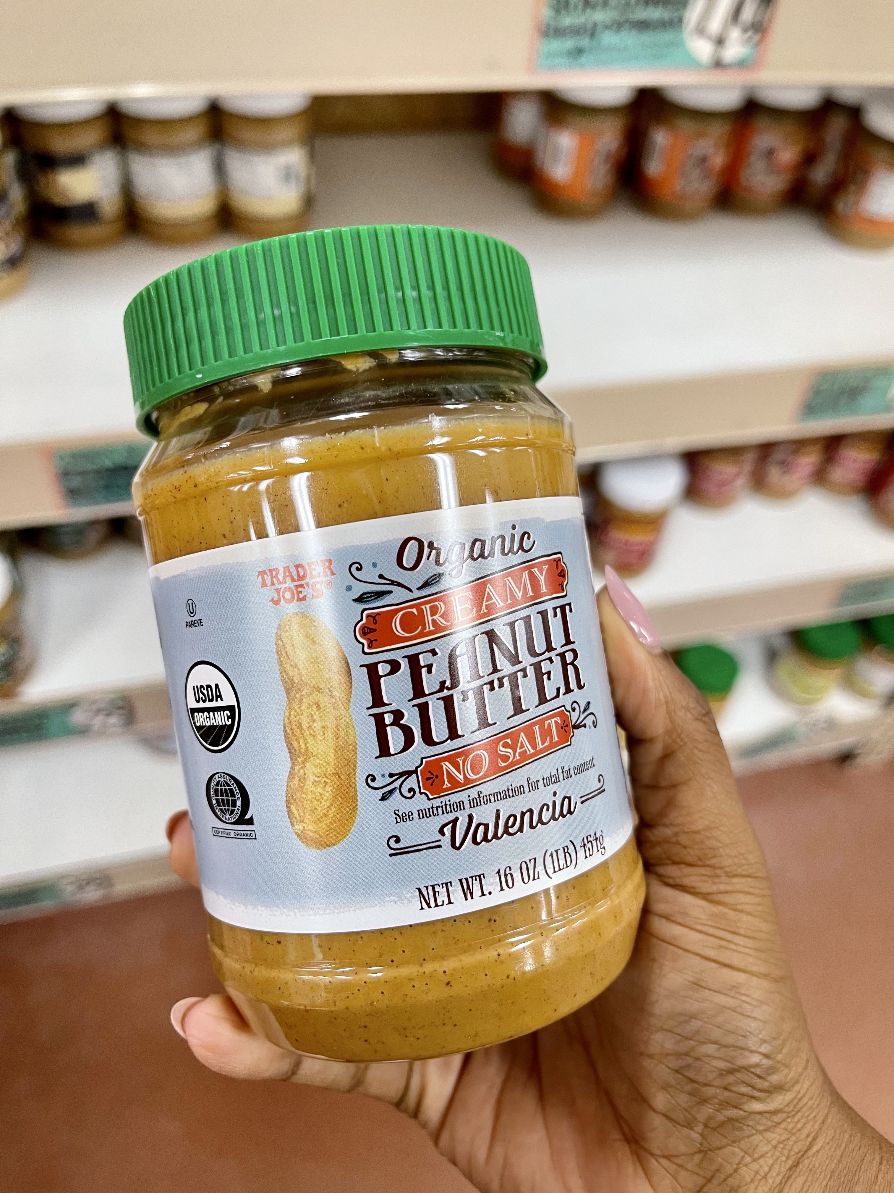 women holding trader joe's organic creamy peanut butter unsalted in the store