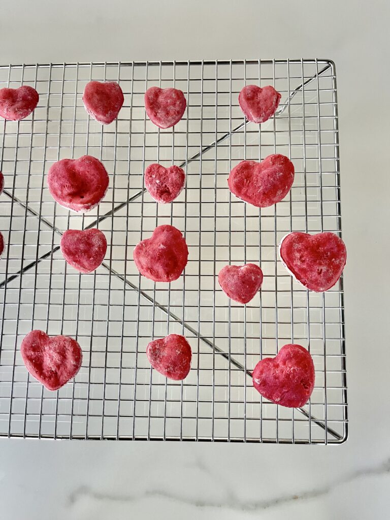 heart shaped beet dog treats lay on a cooling rack