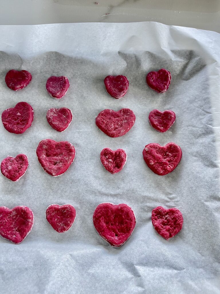 heart shaped beet dog treats lay on a baking pan