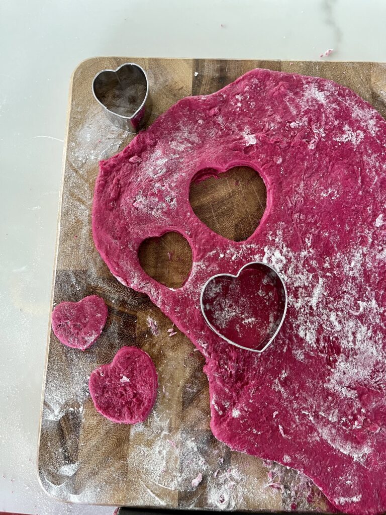 heart beet dog treat dough rolled out with heart shaped cookie cutters
