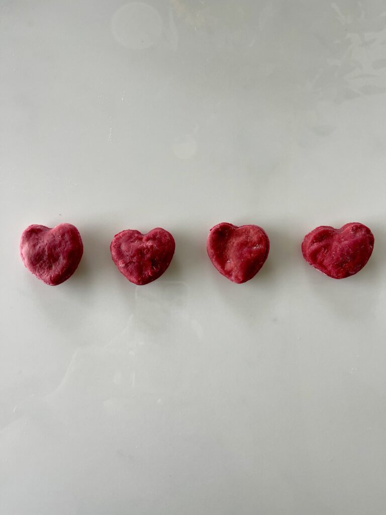 4 heart shaped beet dog treats lay on a kitchen counter