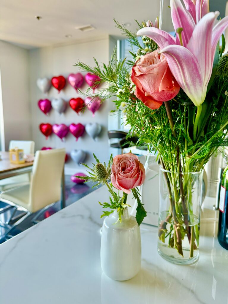 flower bouquets on a kitchen counter with heart shaped balloons on wall